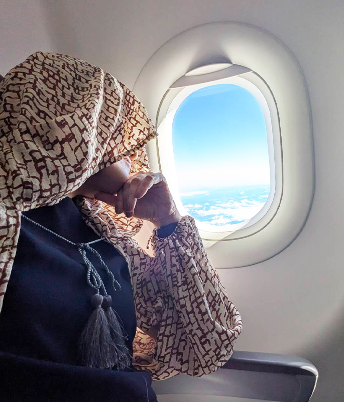飛行機で仮眠をとるときの寝顔隠しとして、ボーホーストールのフードを目元までかぶっているところ