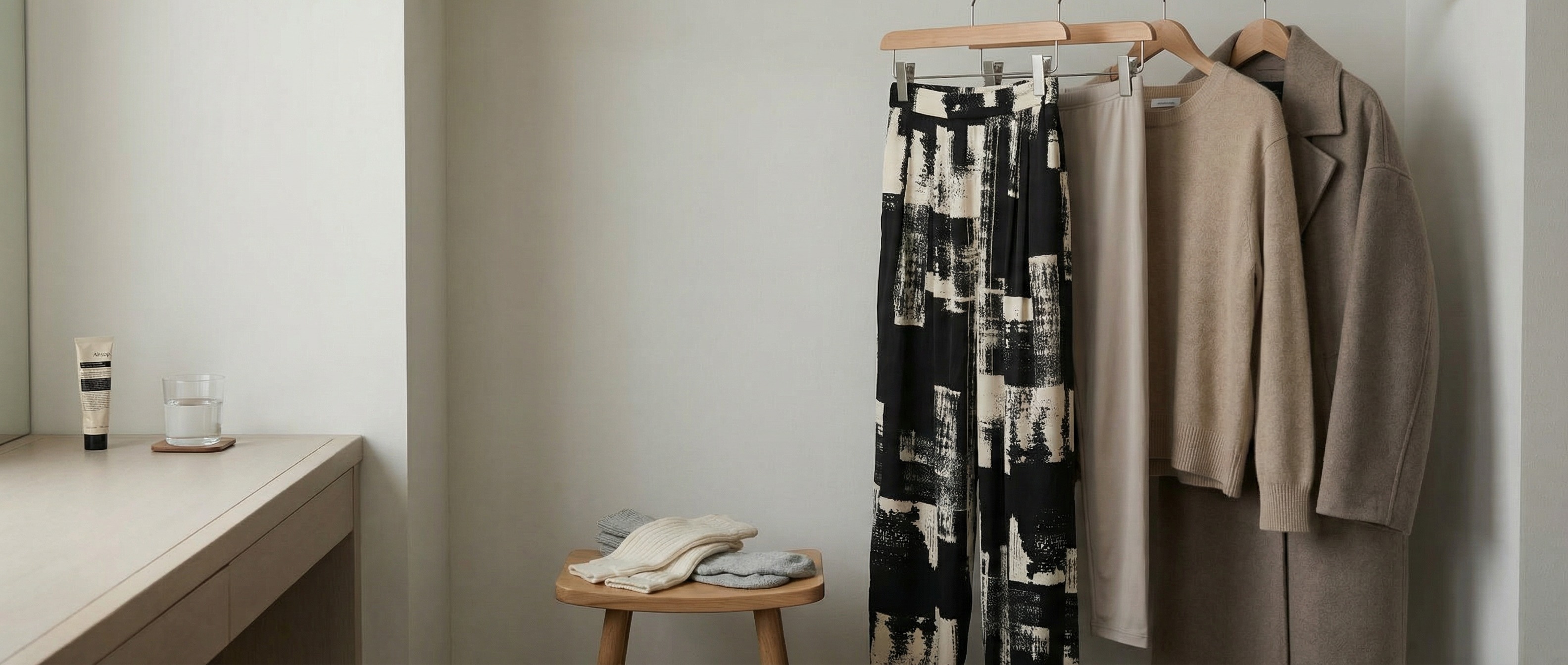 ホテルのクローゼットに並ぶ服と小物。ニュートラルカラー。文字なし。