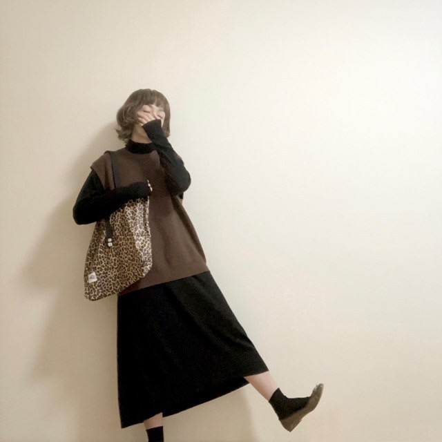 薄手のブラックタートルニットワンピースにブラウンのベストとブラウンのバレエシューズを合わせたシンプル大人カジュアル。レオパード柄のトートバッグがアクセントに。