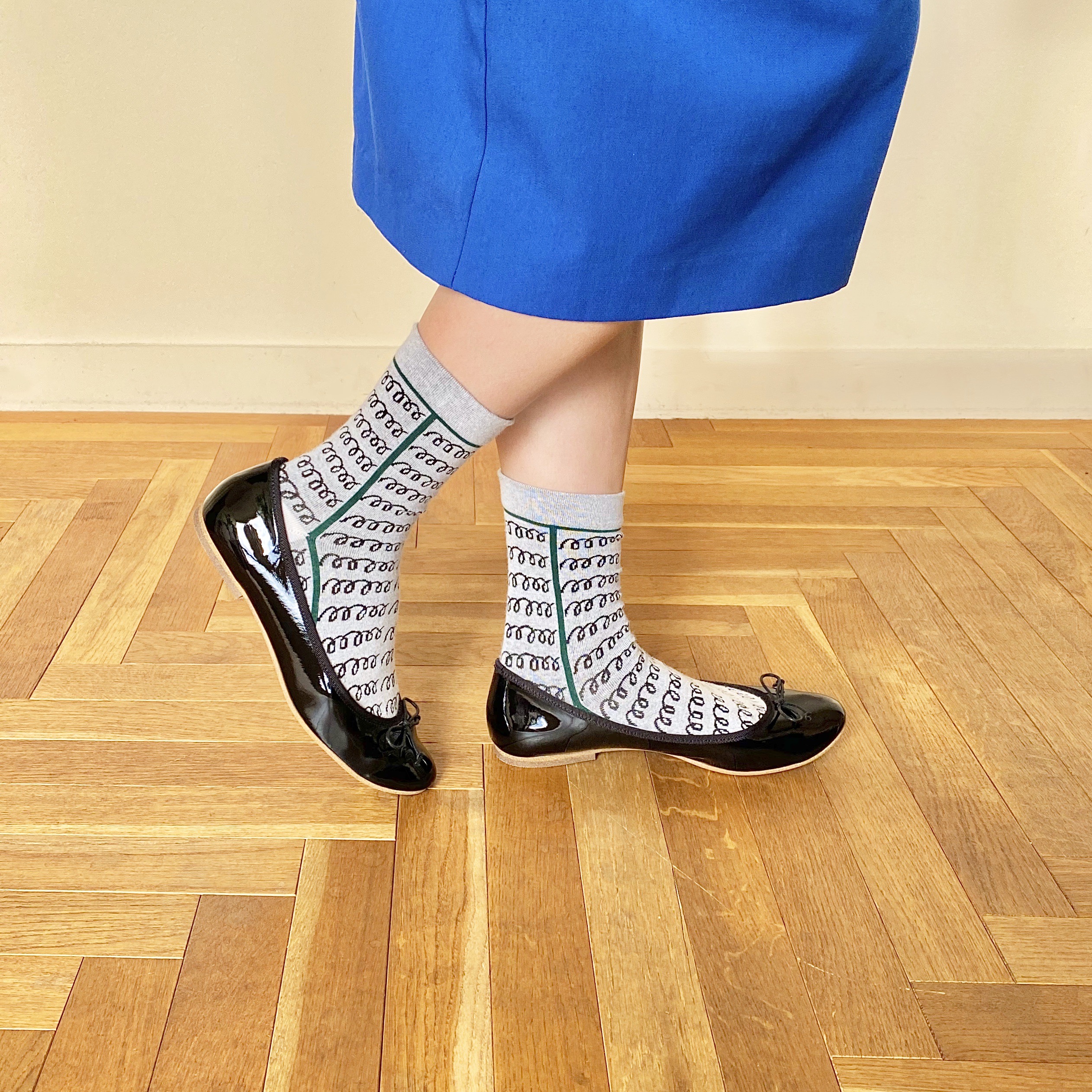 ”青いボックススカートと螺旋模様の靴下と2021年12月10日発売の雑誌「CLUEL（クルーエル）」1月号で紹介されたラウンドトゥのフラットソールエナメルバレエシューズのブラックを合わせた遊び心のあるコーディネート。”/