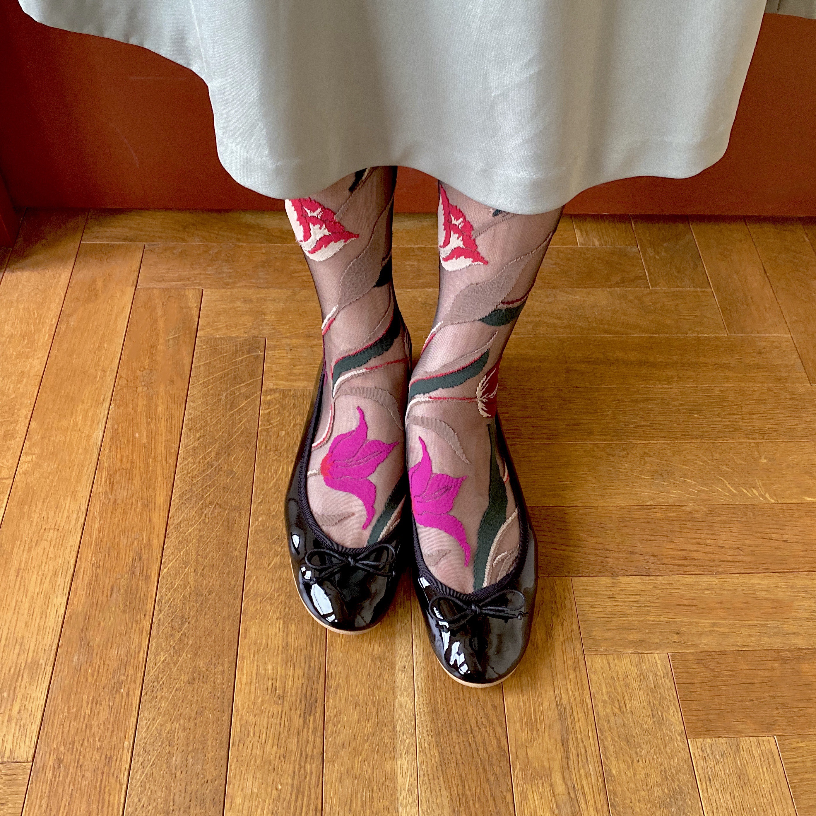 ”2021年12月10日発売の雑誌「CLUEL（クルーエル）」1月号で紹介されたラウンドトゥのフラットソールエナメルバレエシューズのブラックと大胆な花柄シースルーソックスのコーディネート。シースルーソックスは冬はタイツと合わせて色重ねするのもパンプスコーデにおすすめ”/