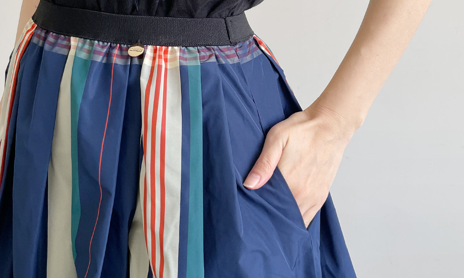 両サイドにはポケットが、左腰にはゴールドのオリジナルチャームがついているTRECODEの神戸・山の手チェック柄スカート　ネイビー×オレンジ
