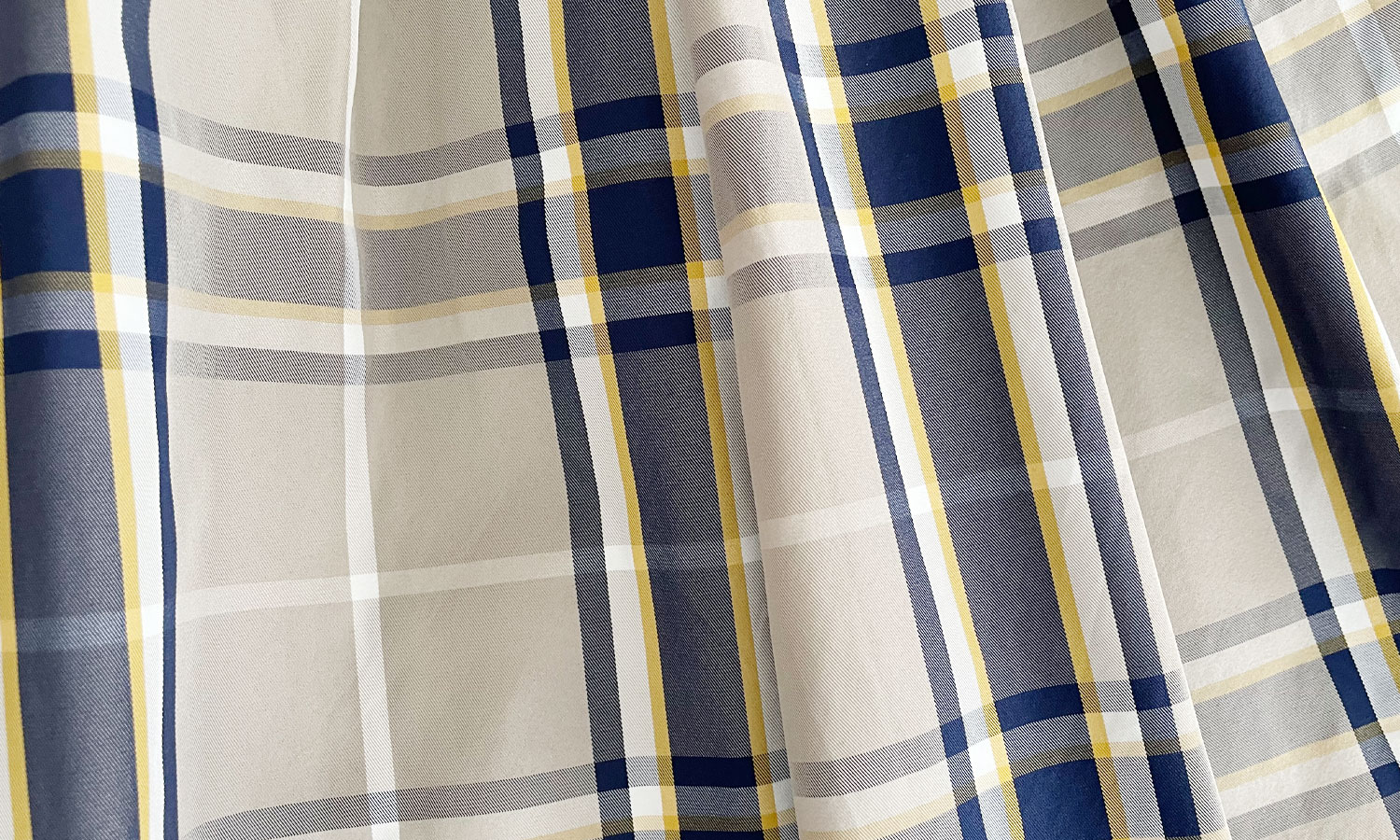 ベージュよりのグレーをベースに薄いネイビーと白・黄色のラインが上品に見えるTRECODEの神戸・山の手チェック柄スカート グレー×ネイビー