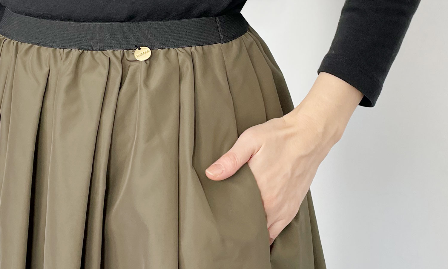 両サイドにはポケットが、左腰にはゴールドのオリジナルチャームがついているTRECODEの神戸・山の手撥水スカート