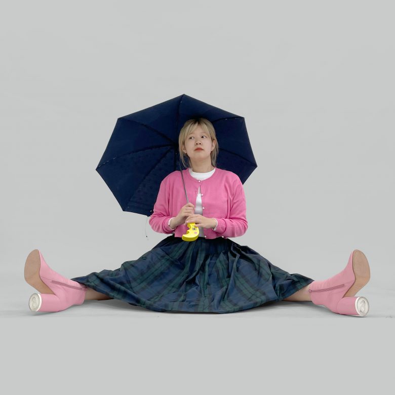 タータンチェックのスカートにピンクのニットとブーツを合わせてキュートなコーディネートに